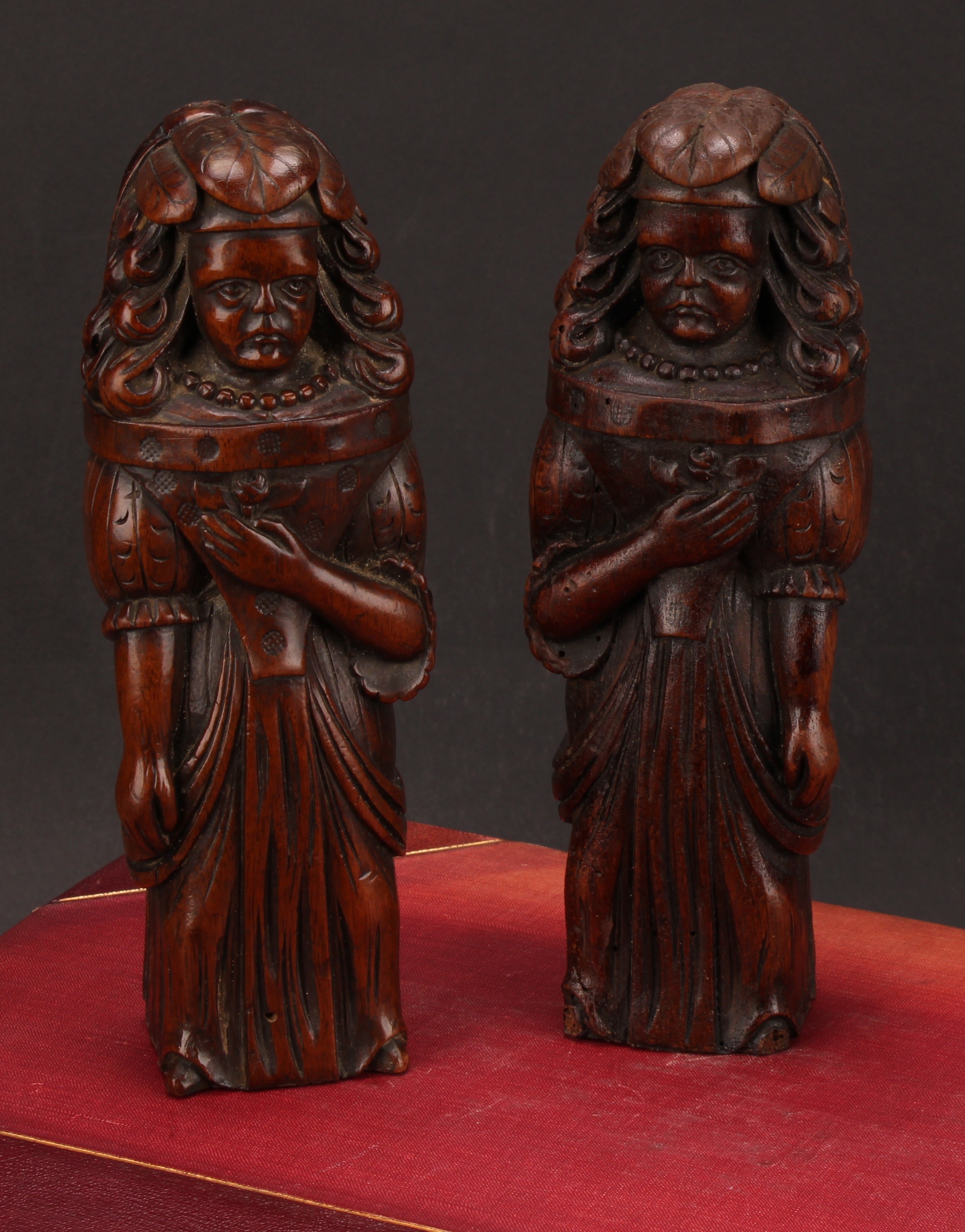 A pair of Continental walnut appliques, each carved as a lady of the court holding a flower to her