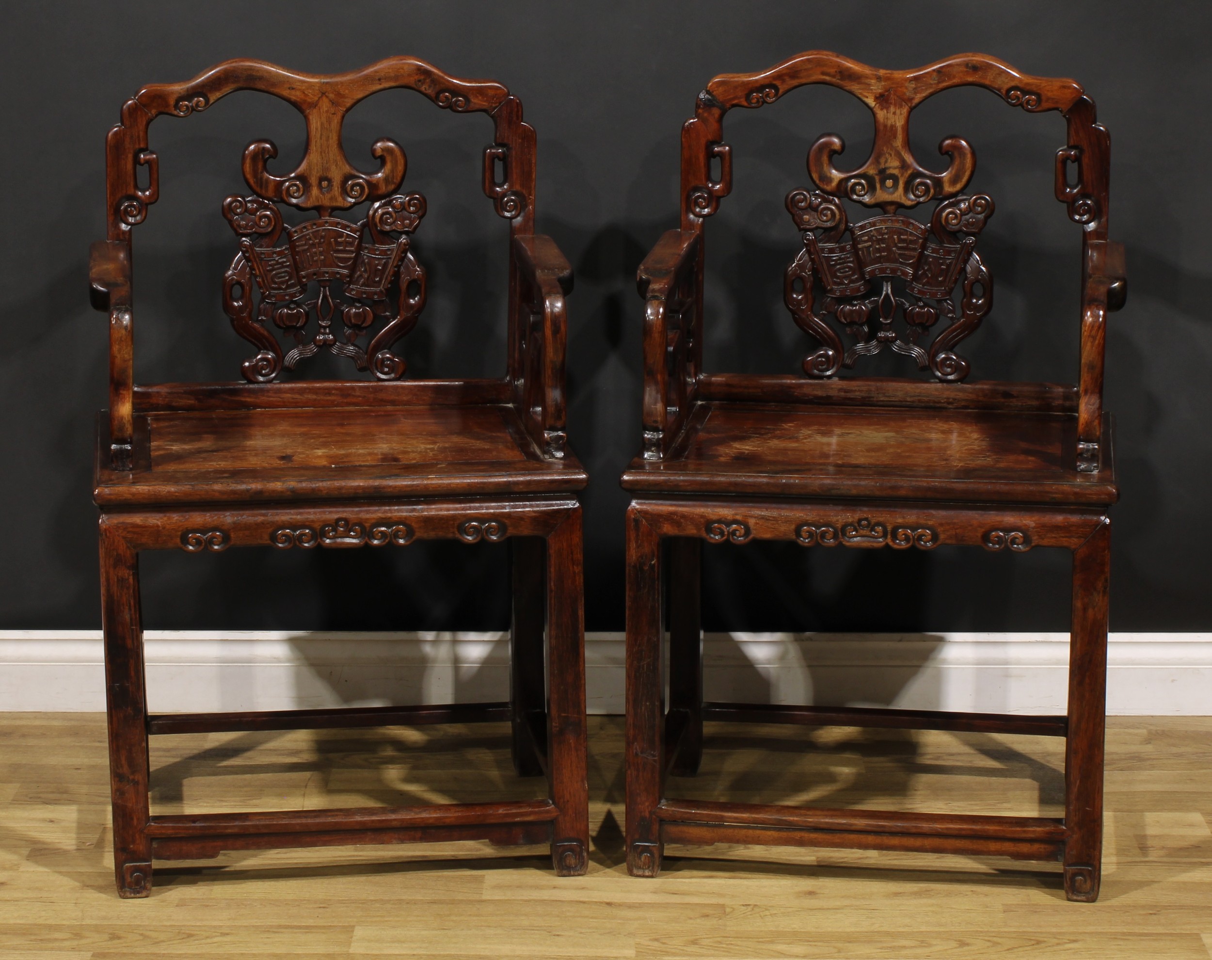 A pair of Chinese hardwood taishi armchairs, each with a shaped back carved with ruyi scepters,