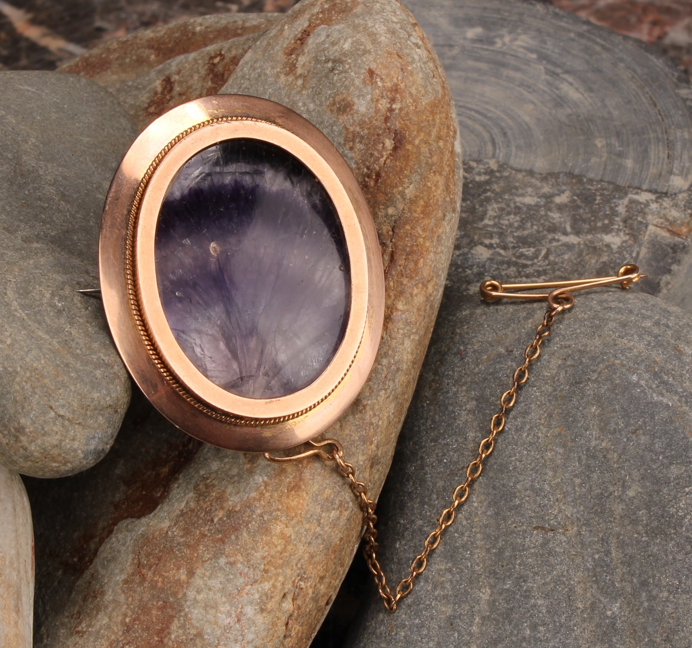 A late 19th century 9ct rose gold Derbyshire Blue John polished oval brooch, the veined panel backed