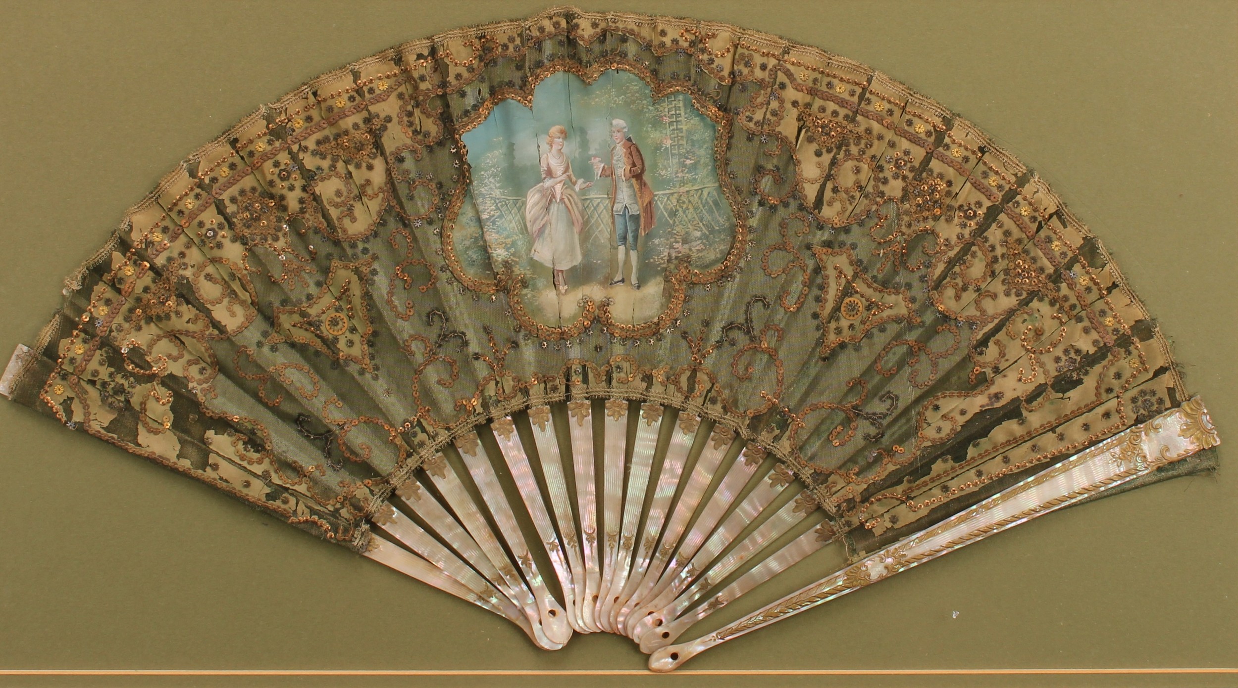 A 19th century French mother of pearl and silk fan, painted with a courting couple, lacking rivet