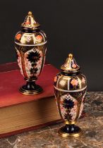 A pair of Royal Crown Derby 1128 Imari pattern slender ovoid pedestal vases, domed covers, gilt ball