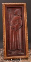 An Arts and Crafts oak panel, carved in relief with a monk inspecting a bundle of fish, gilt