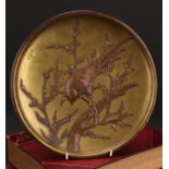 A Japanese gilt and brown patinated bronze dish or charger, applied with a bird perched on a