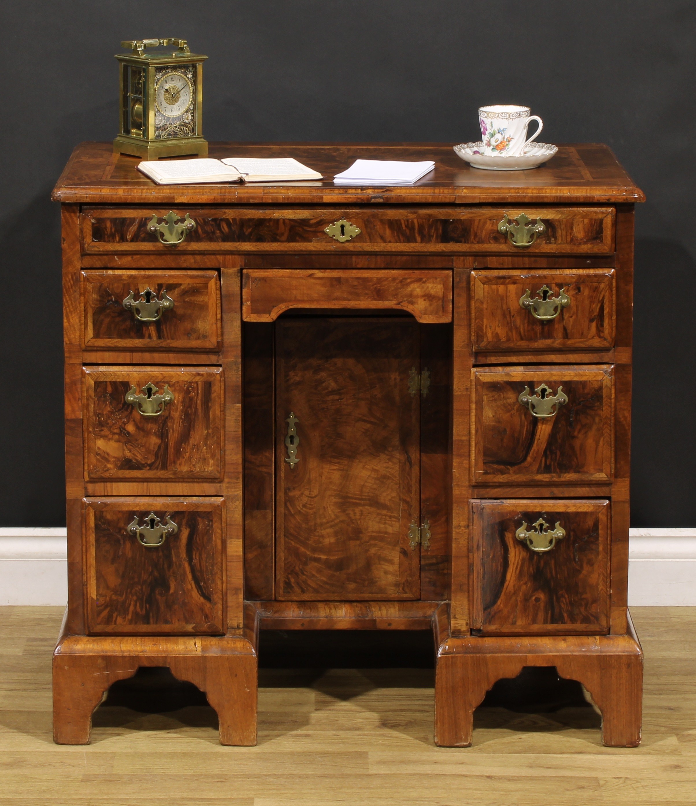 A George II featherbanded walnut kneehole desk, rectangular top with moulded edge above an