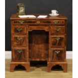 A George II featherbanded walnut kneehole desk, rectangular top with moulded edge above an