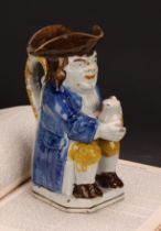 An early 19th century Prattware Toby jug, seated holding a jug of foaming ale, painted in polychrome