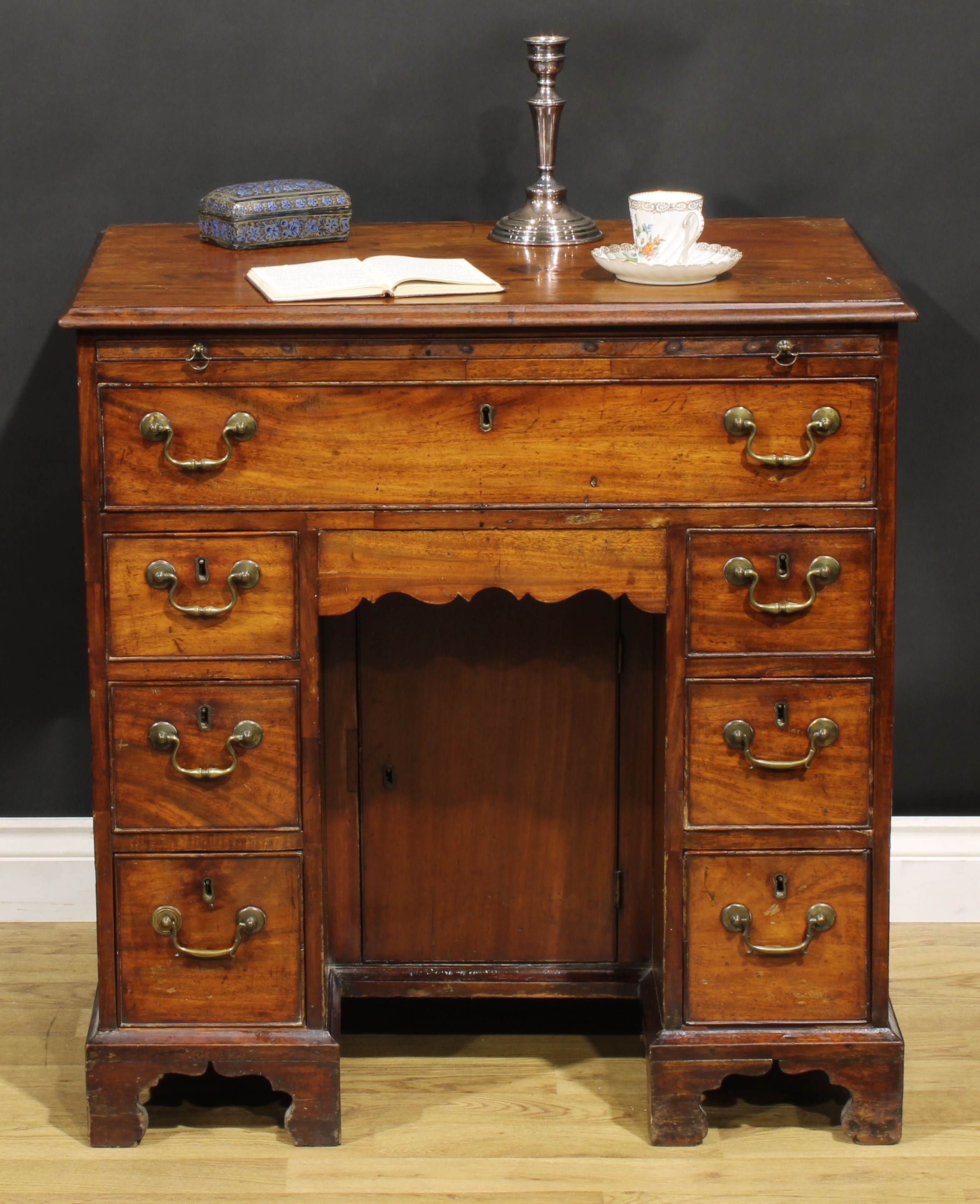 A George III mahogany kneehole desk, the ovolu moulded top above a brushing slide, axe head handles,