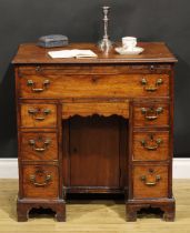 A George III mahogany kneehole desk, the ovolu moulded top above a brushing slide, axe head handles,