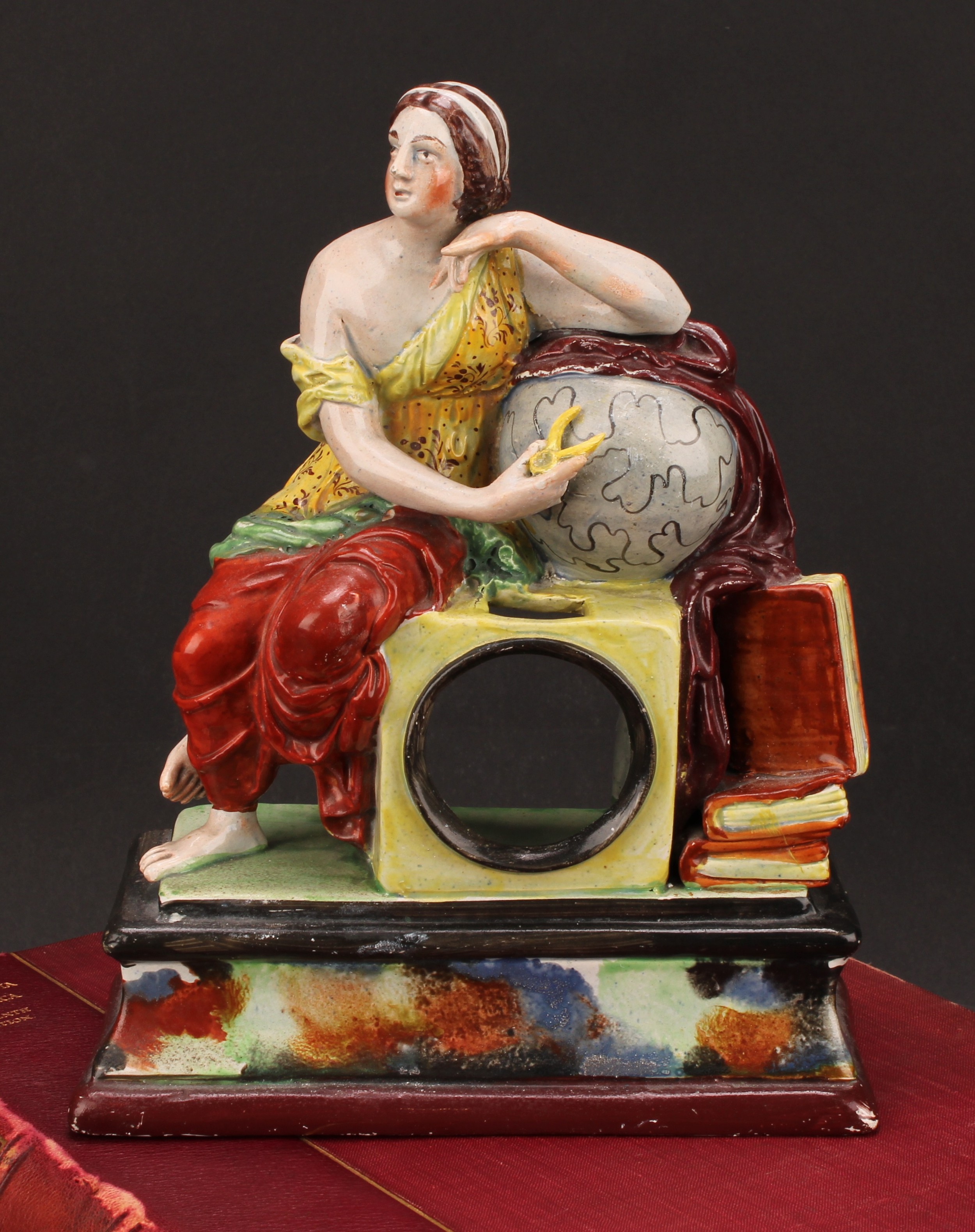 A Staffordshire pearlware pocket watch stand, modelled as Urania, The Muse of Astronomy, seated upon