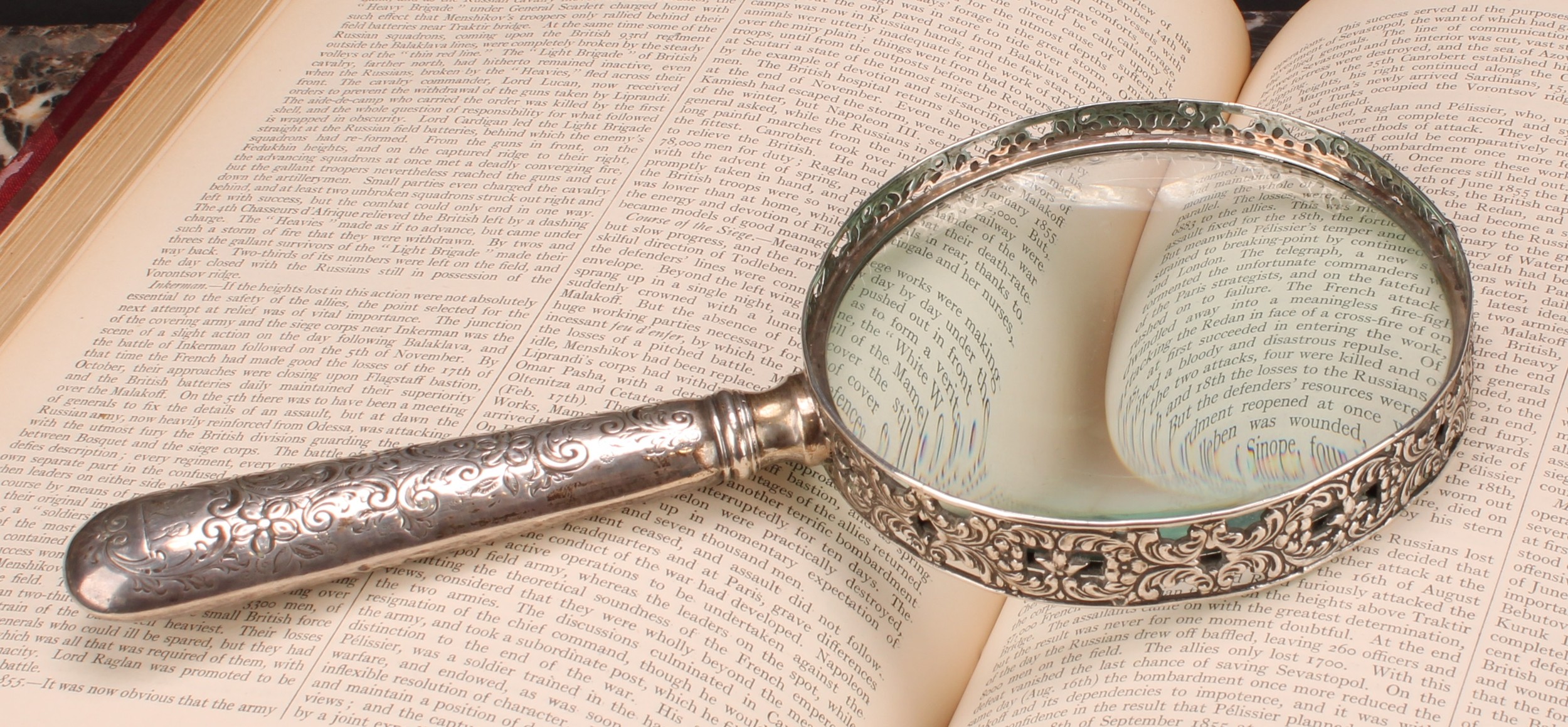 A Victorian silver magnifying glass, the bezel pierced and cast with flowering foliate scrolls,