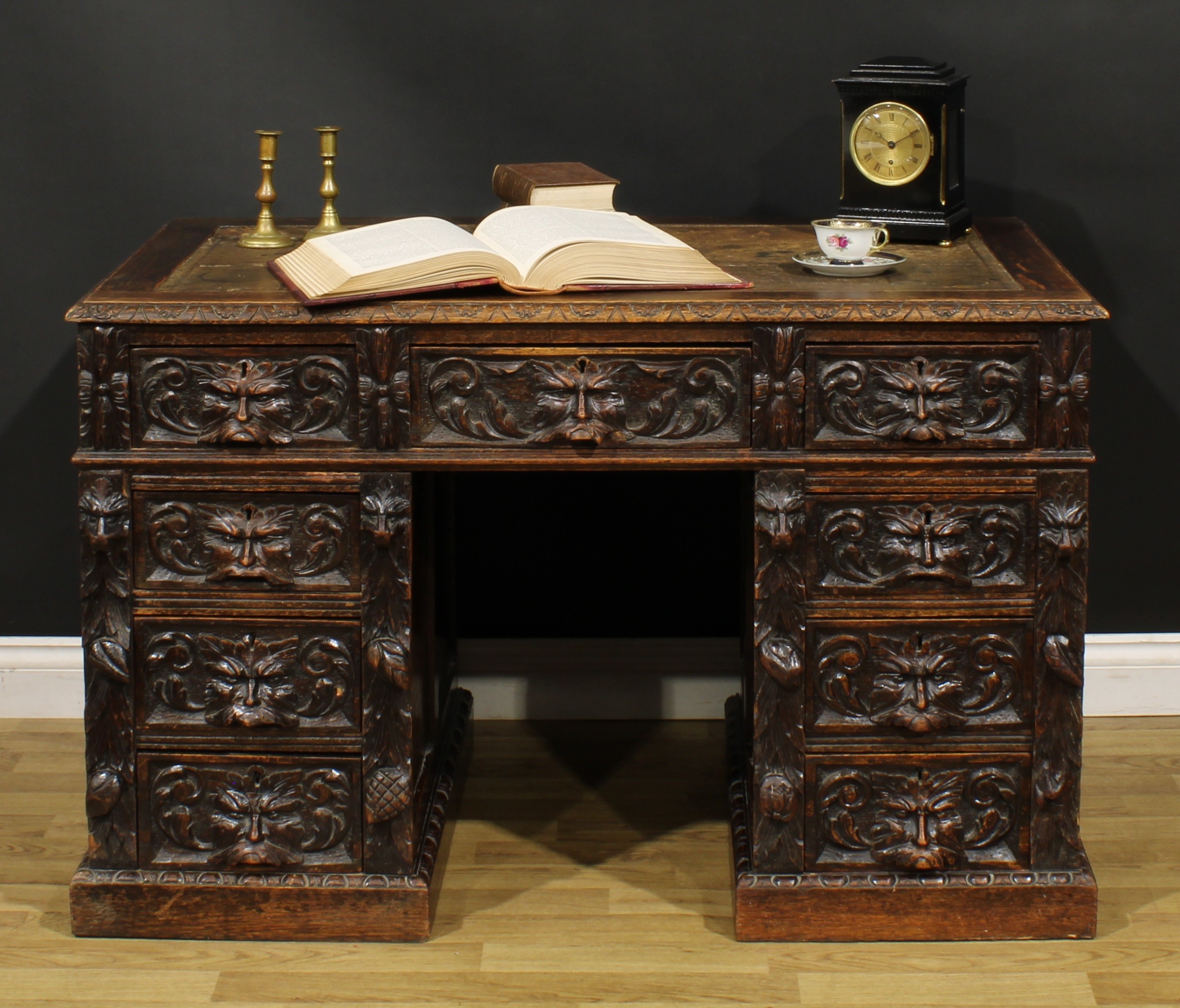 A late Victorian oak twin pedestal desk, rectangular top with foliate carved edge and inset