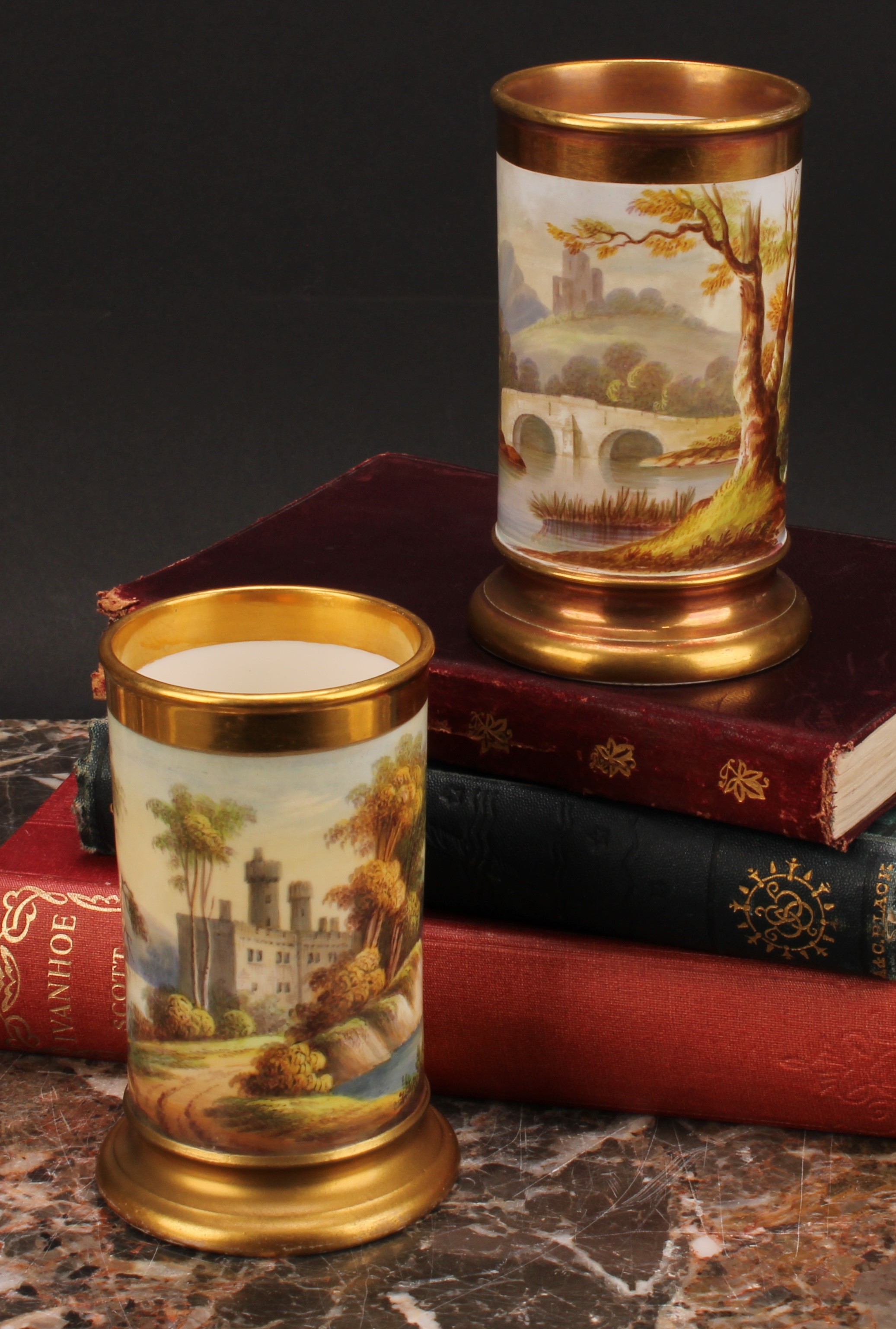 A pair of English porcelain cylindrical spill vases, each painted with a continuous lakeside