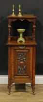 A late Victorian Aesthetic Movement oak fireside purdonium, the fall front set with a panel carved