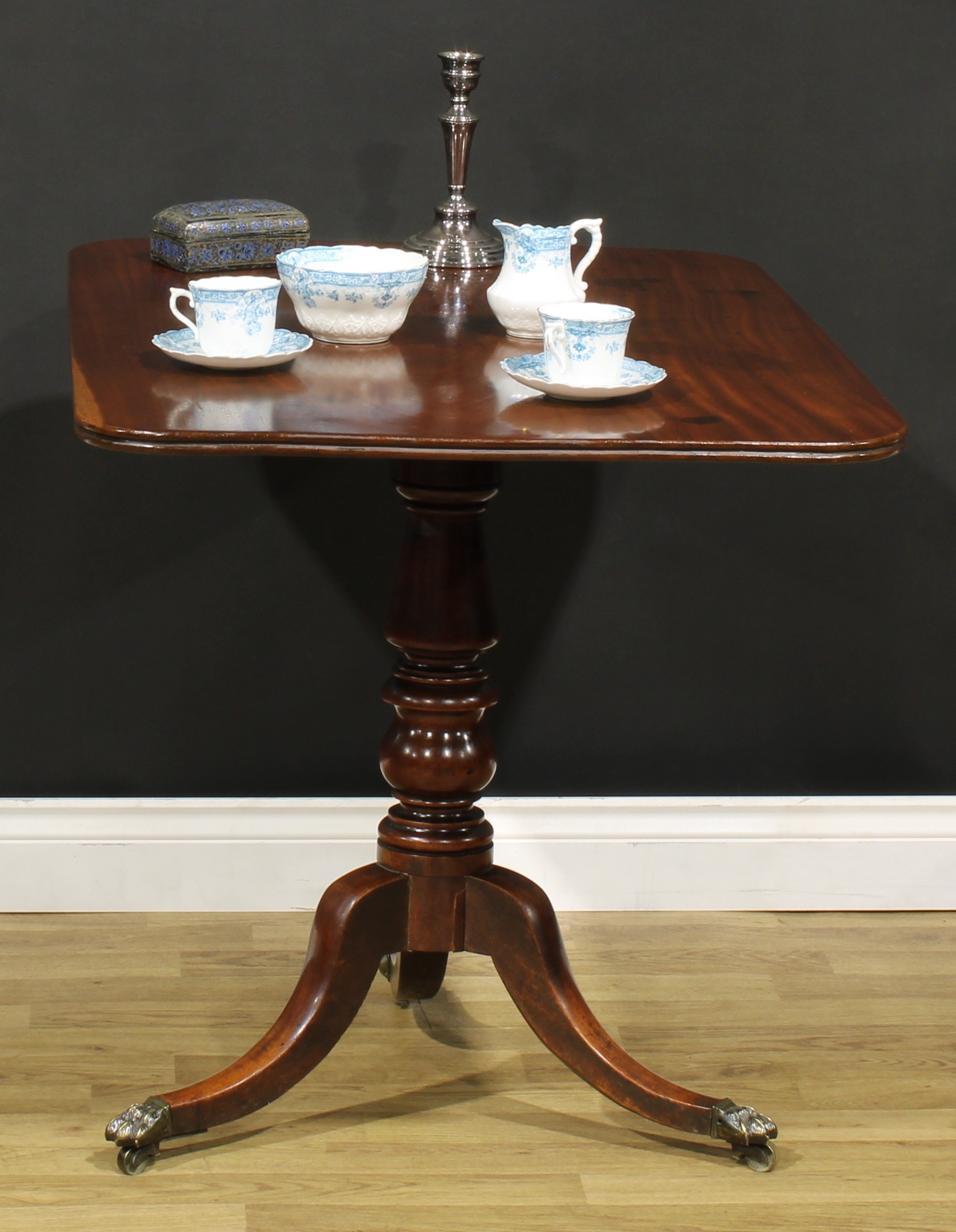 A Regency mahogany tripod supper table, rounded rectangular tilting top with channelled edge, turned