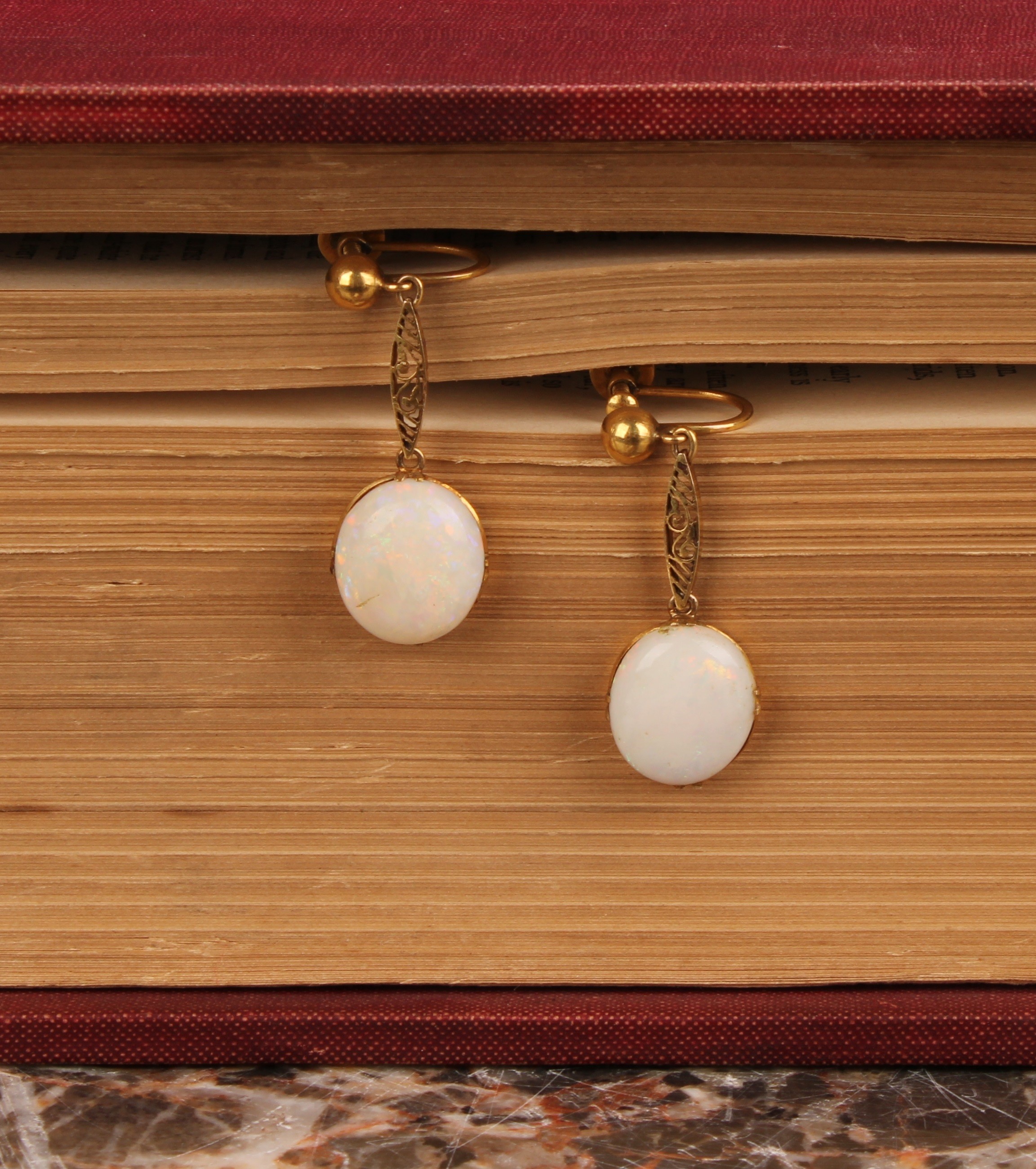 A pair of opal drop earrings, each with a single oval polished opal cabochon, unmarked yellow