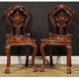 A pair of Victorian mahogany hall chairs, each with a shaped back centred by a vacant cartouche,