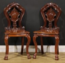 A pair of Victorian mahogany hall chairs, each with a shaped back centred by a vacant cartouche,