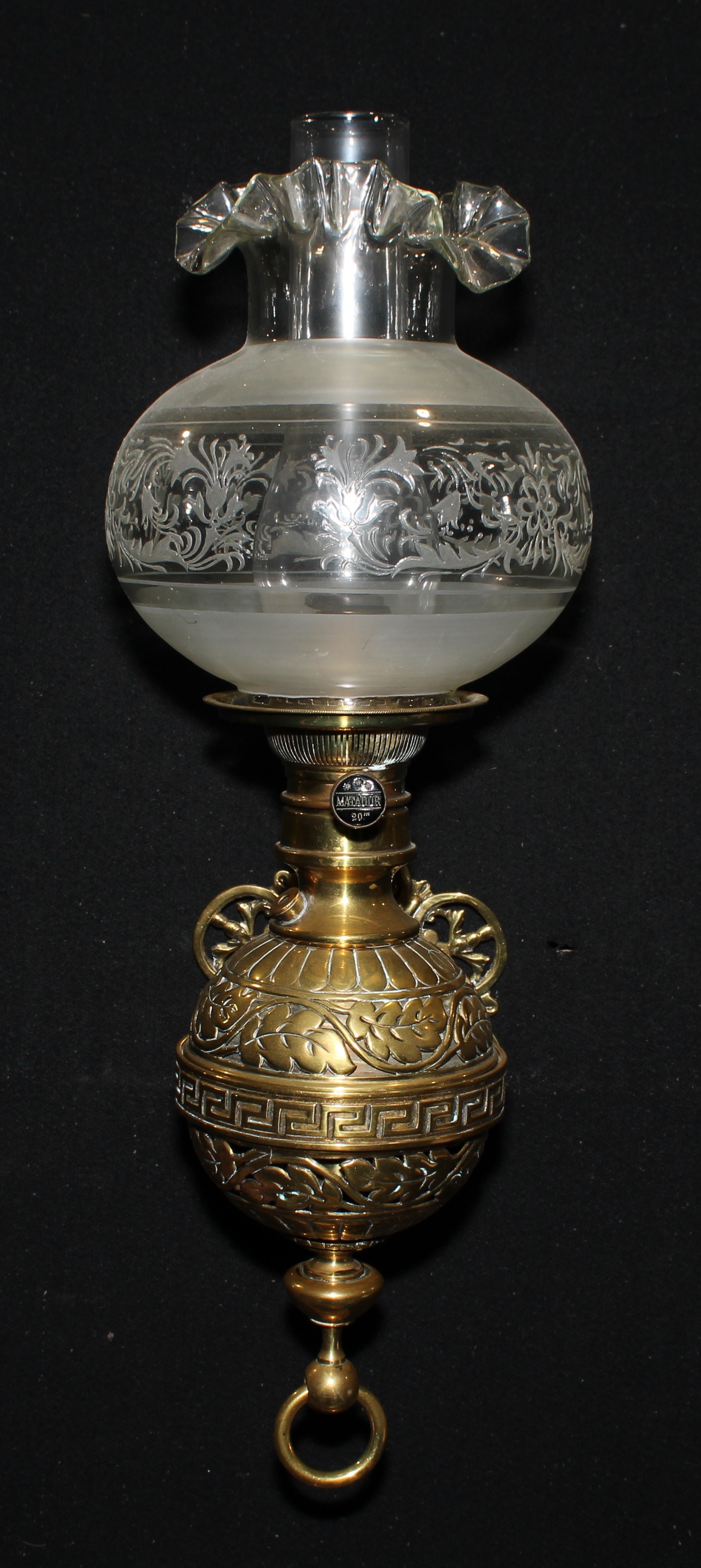 A 19th century brass wall mounted globular oil lamp, cast with foliate scrolls and Greek key border,
