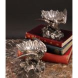 A pair of Baroque design sculptural silver plated salts, each cast as an eagle supporting a shell,