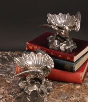 A pair of Baroque design sculptural silver plated salts, each cast as an eagle supporting a shell,