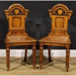 A pair of Victorian oak hall chairs, each shaped back with moulded chapeau de gendarme cresting