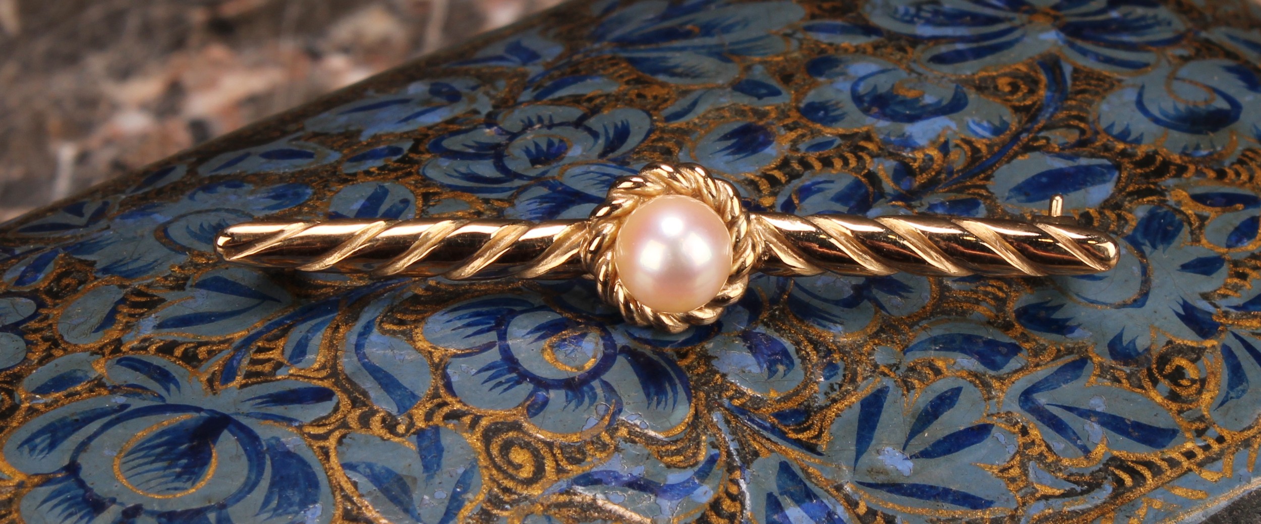 A 9ct gold and pearl tie pin, the central cultured pearl set within a rope twist circular border