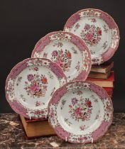 A set of four 18th century Chinese export shaped circular soup plates, painted in the famille rose