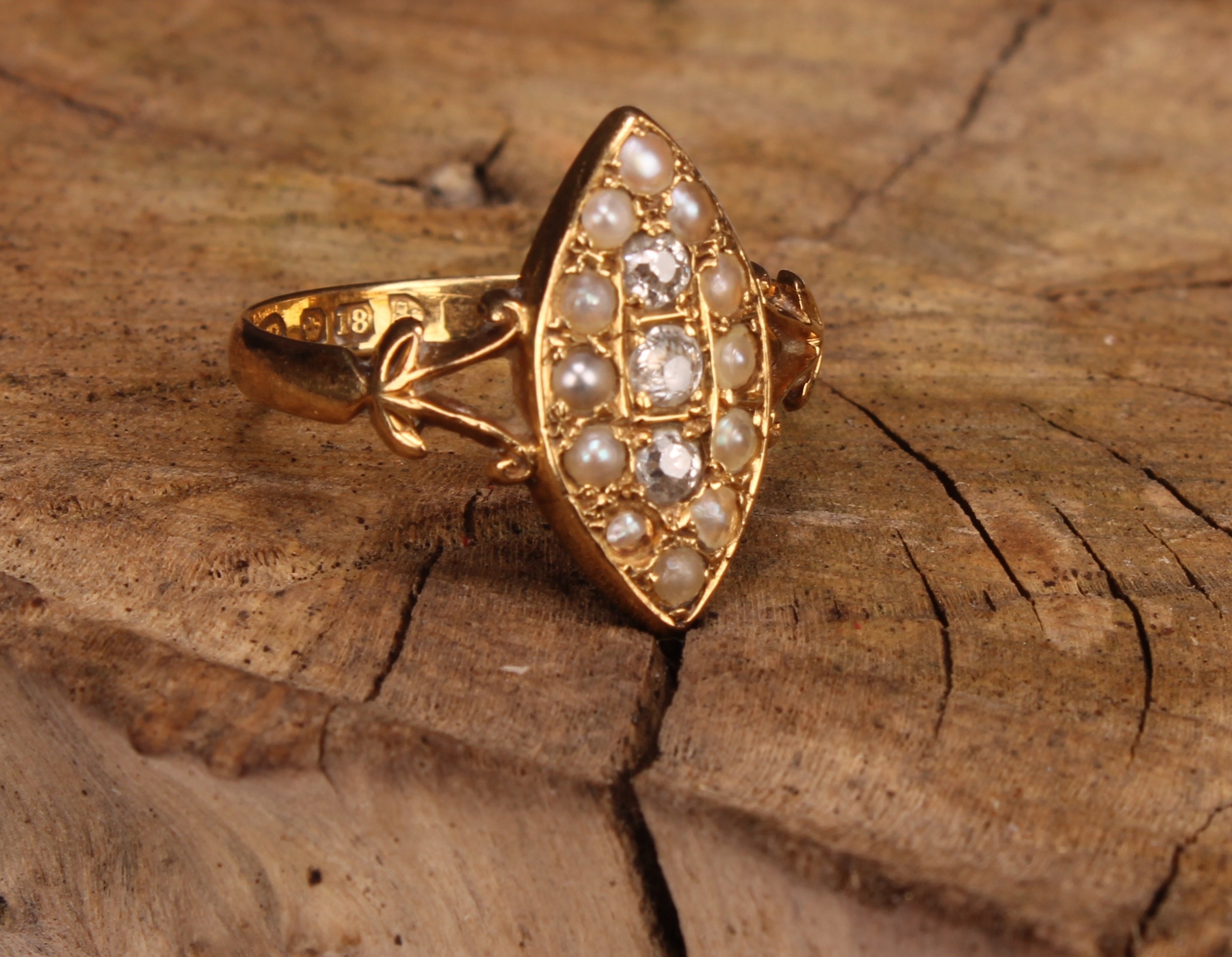 A diamond, seed pearl and 18ct gold navette shaped ring, set with three diamonds within 12 seed