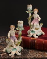 A pair of Continental porcelain figural candlesticks, probably Samson, modelled with seated putto,