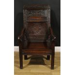 A 17th century oak wainscot armchair, rectangular panel back carved with lozenges and leafy scrolls,