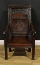 A 17th century oak wainscot armchair, rectangular panel back carved with lozenges and leafy scrolls,