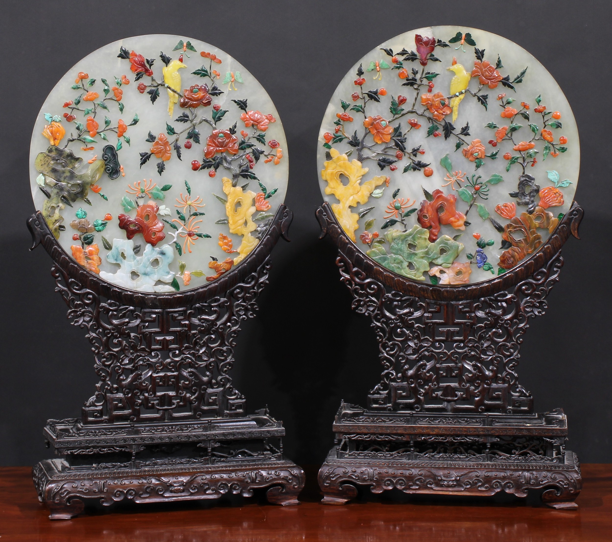 A pair of Chinese hardstone table screens, each circular tablet applied in coloured specimens with