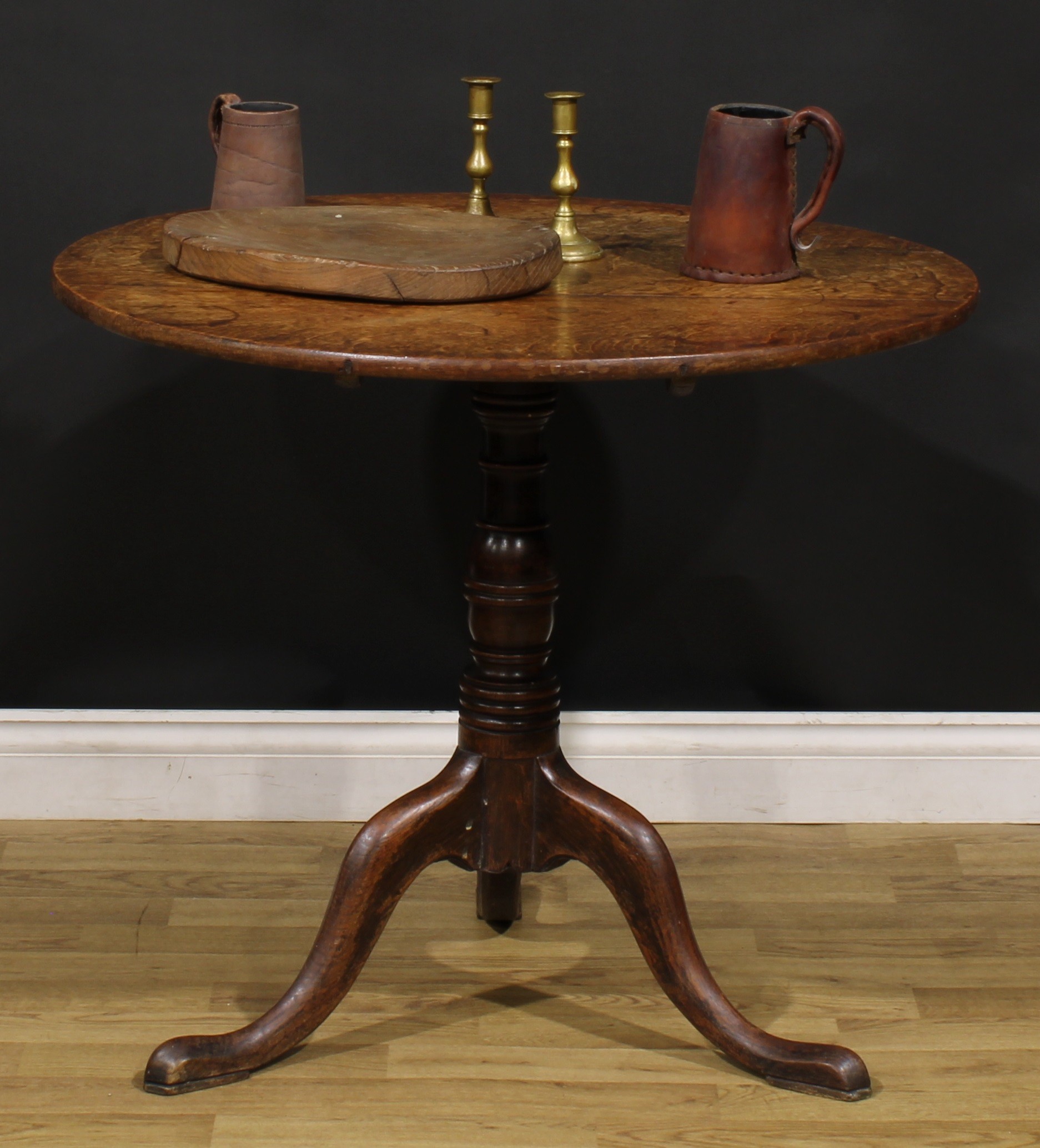 A George III oak tripod occasional table, circular tilting top, turned column, cabriole legs, pad