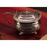 A George IV silver boat shaped mustard, hinged cover, gadrooned border, angular scroll handle,