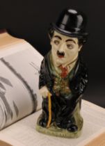 A Royal Doulton jug and cover, modelled as Charlie Chaplin, he stands wearing baggy black suit