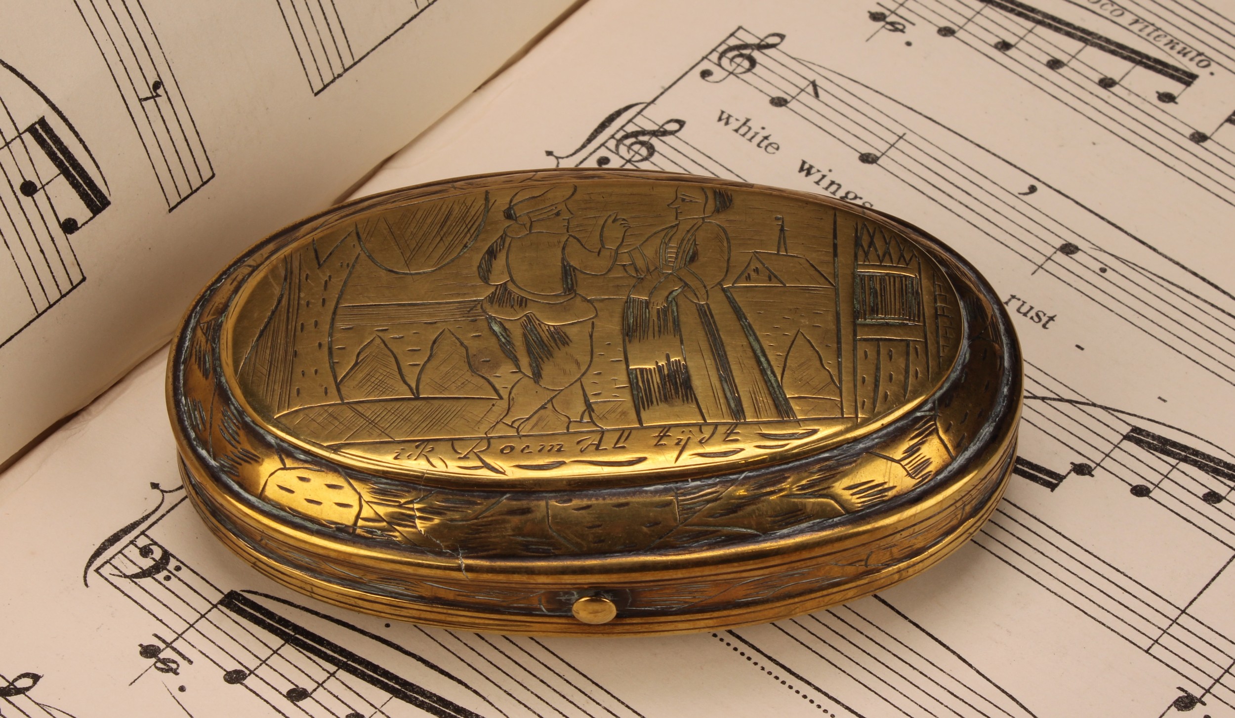 An early 18th century Dutch brass oval tobacco box, engraved with narrative scenes, hinged cover