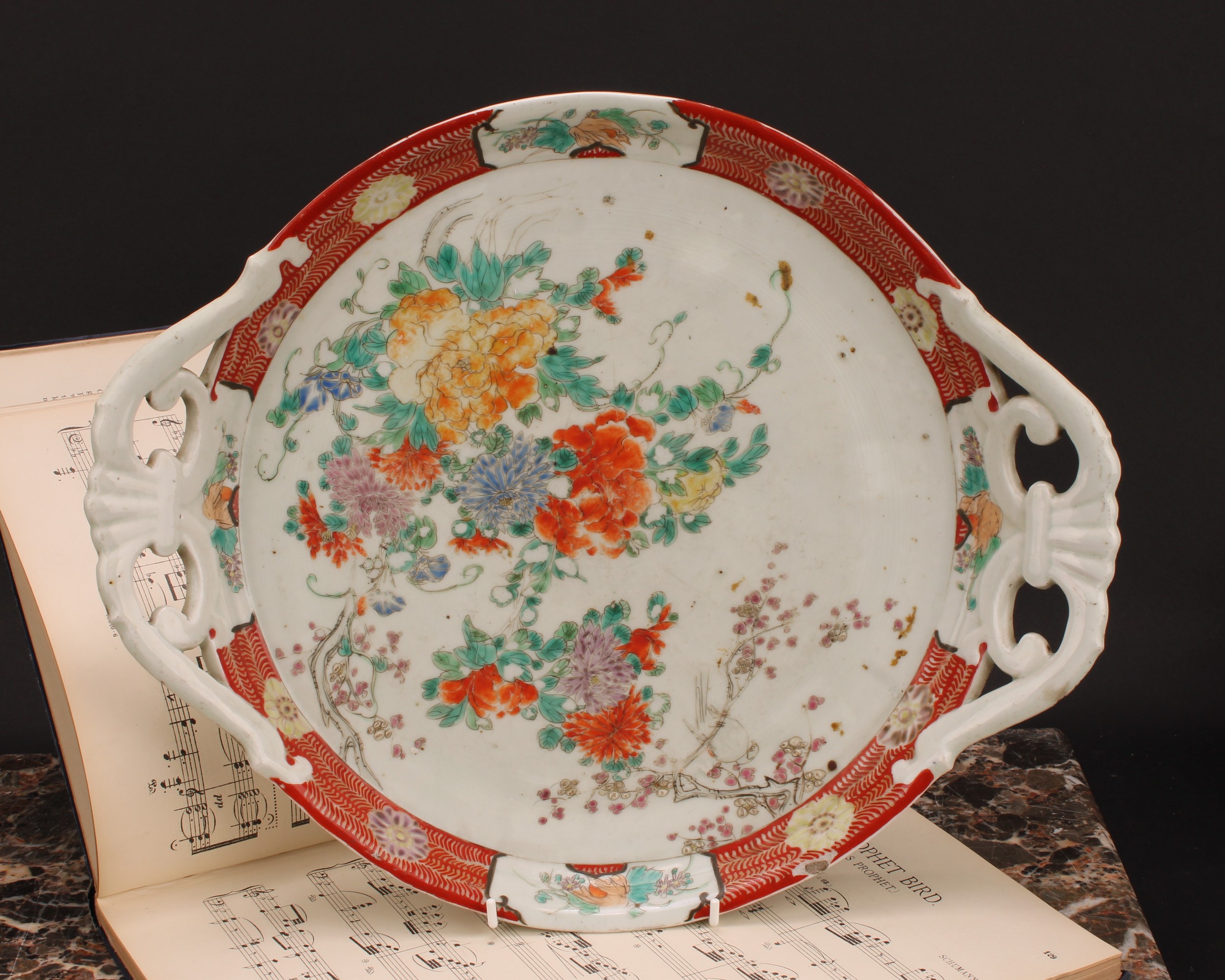 A Japanese two-handled circular tray, painted in polychrome with flowers, 41cm wide, Meiji period