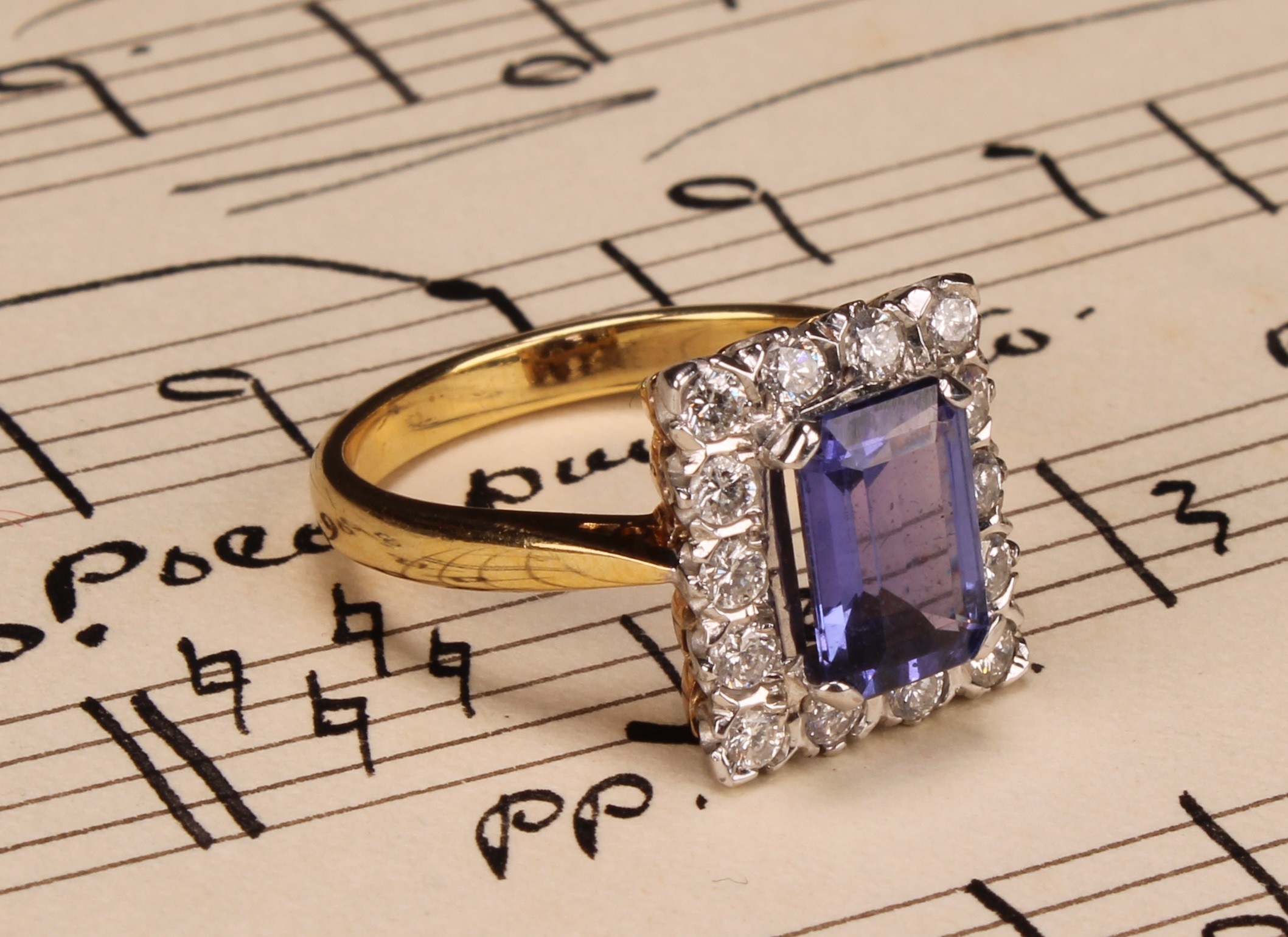 A tanzanite and diamond ring, the rectangular cushion cut stone claw set within a single band of