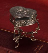 A Continental silver novelty trinket box, as a heart shaped table, embossed with putti, scroll legs,