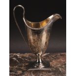 A George III silver helmet shaped cream jug, bright-cut engraved and outlined with wrigglework,