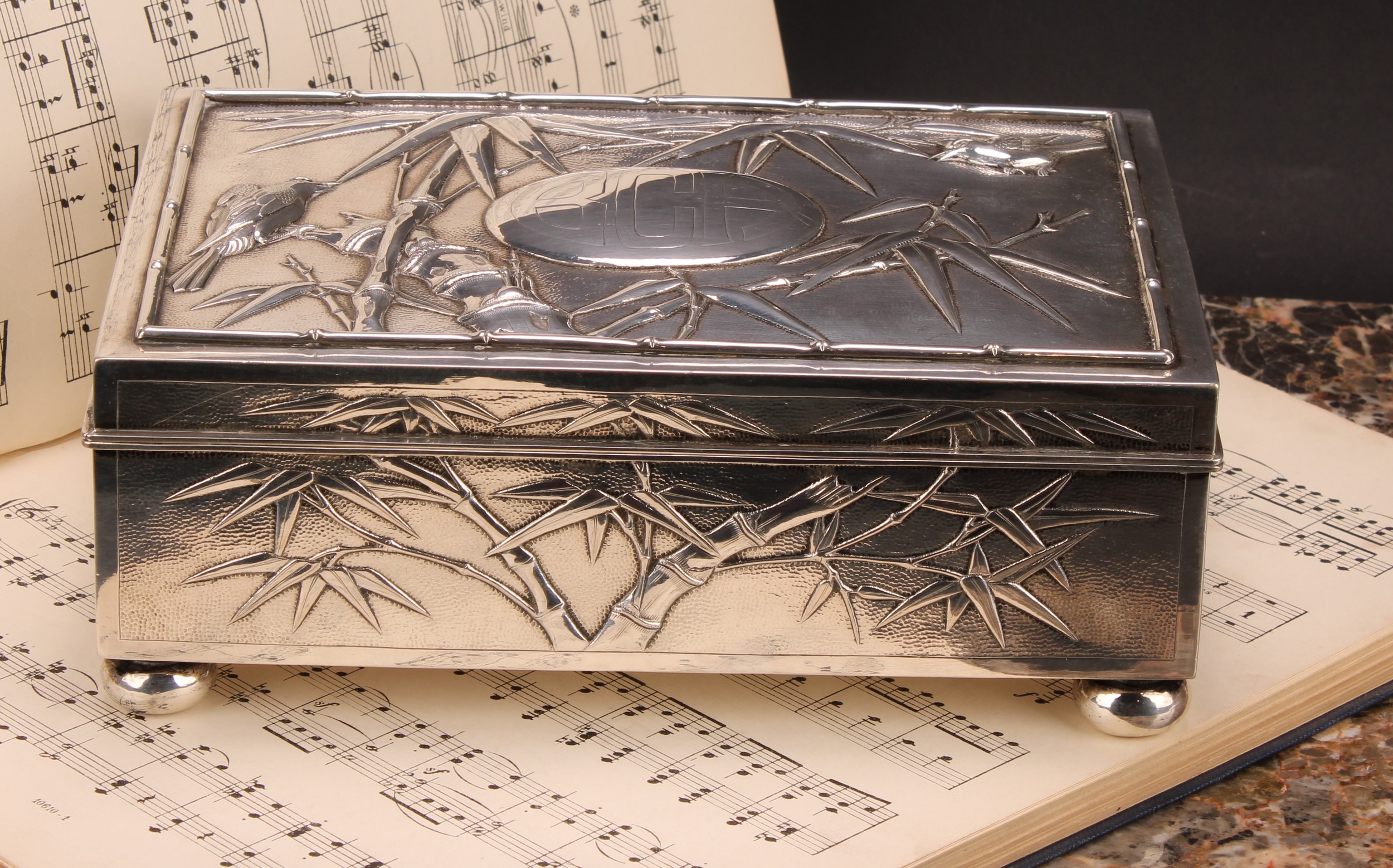 A large Chinese silver rectangular cigar box, chased with birds amongst leafy bamboo, hinged