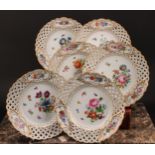 A set of six German porcelain shaped circular plates, decorated with flowers, pierced borders picked