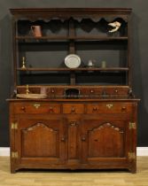 A George III oak dresser, moulded cornice above a pair of shelves, the projecting base with