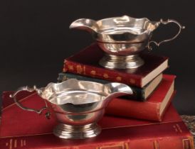 A pair of early George II silver sauce boats, wavy borders, scroll handles, cast bases, 19.5cm long,