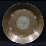A large Islamic copper dish, chased with a central lozenge within six lotus reserves, calligraphy