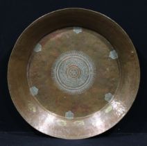 A large Islamic copper dish, chased with a central lozenge within six lotus reserves, calligraphy