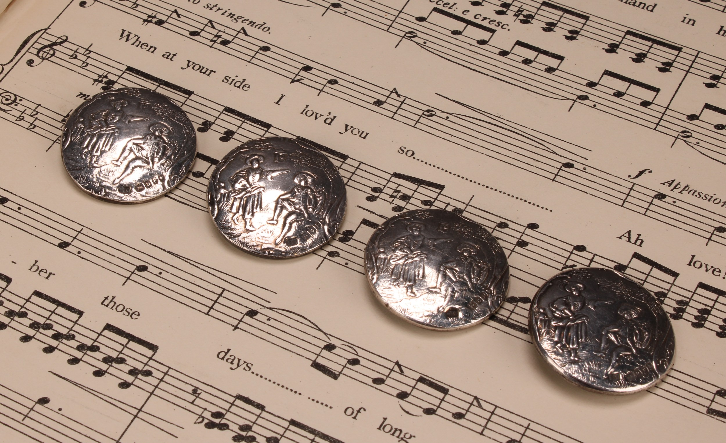 A set of four Continental silver buttons, chased with courting couples, 3.5cm diam, import marks for