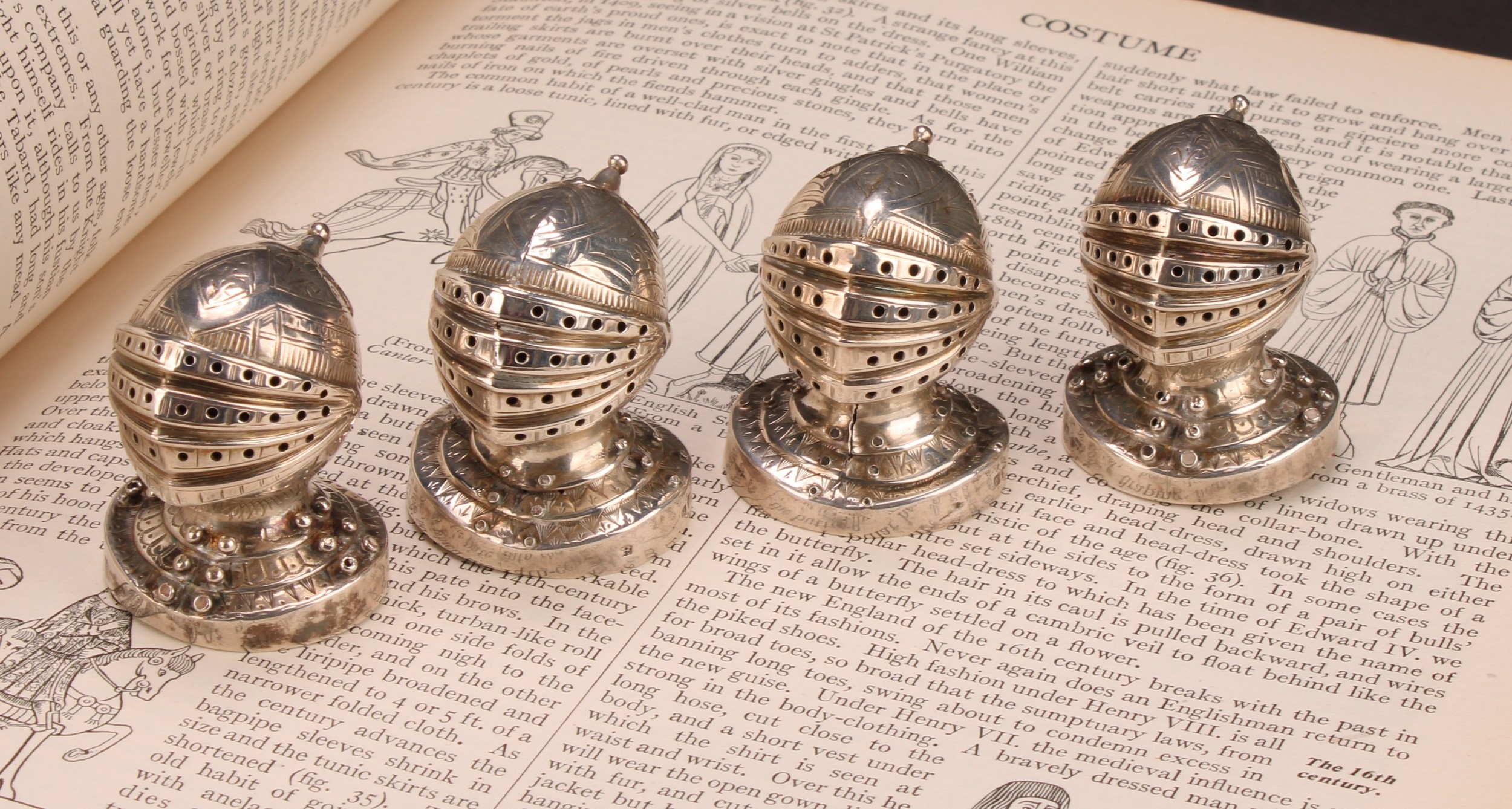 A set of four Victorian Gothic Revival silver novelty peppers, each as a knight's helmet and