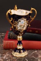 A Coalport three-handled pedestal ovoid cup or vase, painted with a landscape, within an shaped