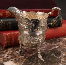 A Victorian silver cream jug, of 18th century Irish design, profusely chased with animals, flowers